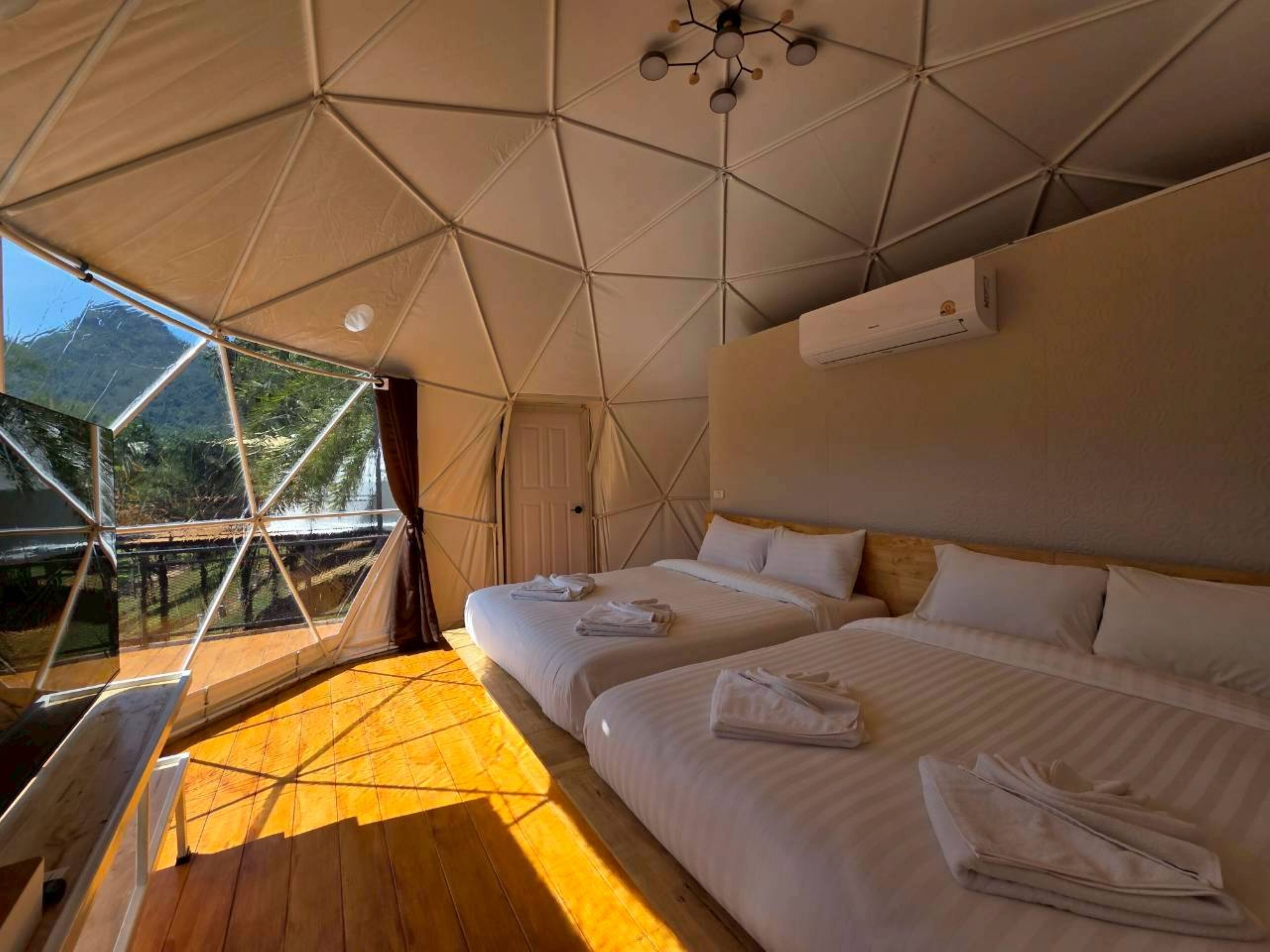 A tent-style room with two beds, a ceiling fan, and an air conditioning unit.