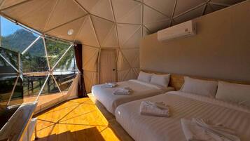 A tent-style room with two beds, a ceiling fan, and an air conditioning unit.