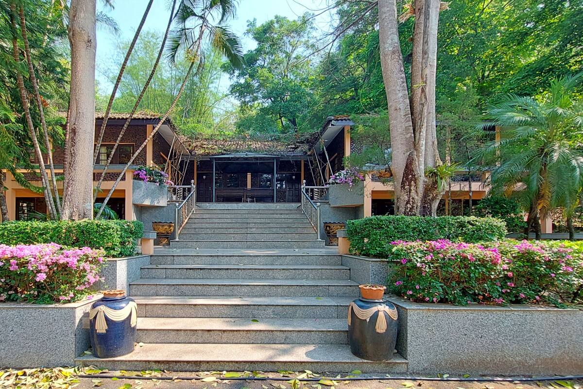 A staircase leading to a building surrounded by lush greenery and flowering plants.