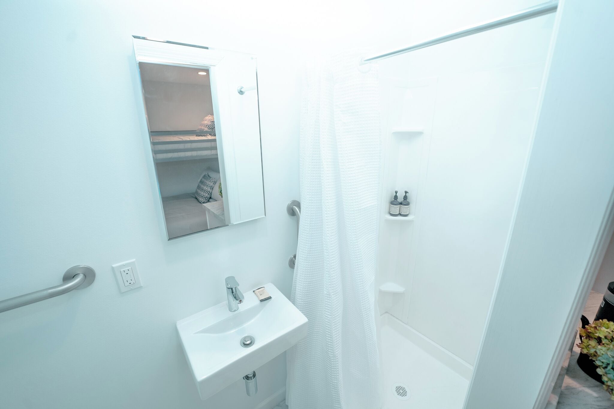 A bathroom with a white sink, mirror, and shower curtain.