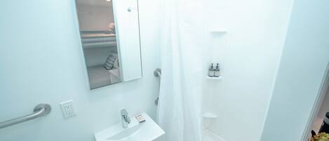 A bathroom with a white sink, mirror, and shower curtain.