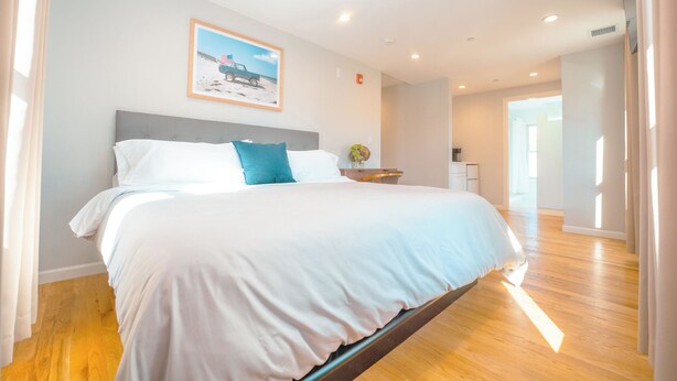 Une chambre d’hôtel moderne avec un grand lit, un tableau encadré au mur et un plancher en bois.