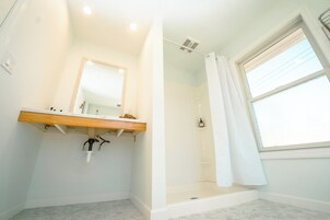 Un baño con tocador de madera, espejo, cabina de ducha y ventana.