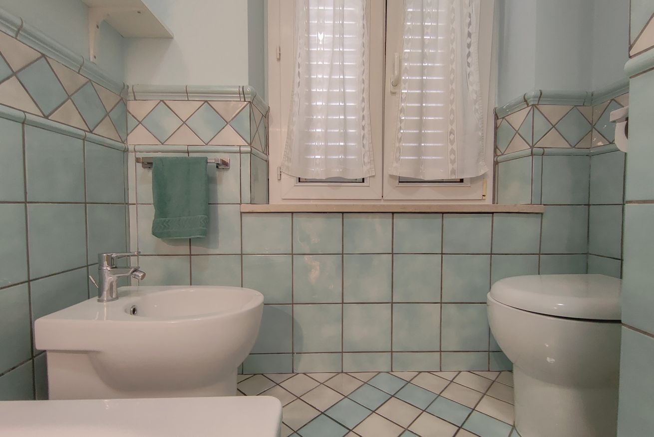 A bathroom with a sink, toilet, and window with shutters.