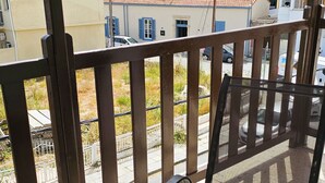 Egy erkély, melyen üveglapból készült asztal és székek találhatók, és ahonnan egy több eréllyel ellátott, vörös cseréptetős szállodai épületre nyílik kilátás.
