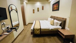 A hotel room with a bed, bedside table, TV, and a mirror. - Hotel The Golf (Lucknow)