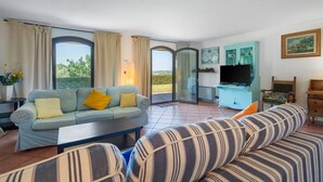 Ein Wohnzimmer mit Sofa, gestreifter Couch, Fernseher und Schrank.