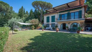 Ein zweistöckiges Haus mit Balkon, Swimmingpool und gepflegtem Garten.