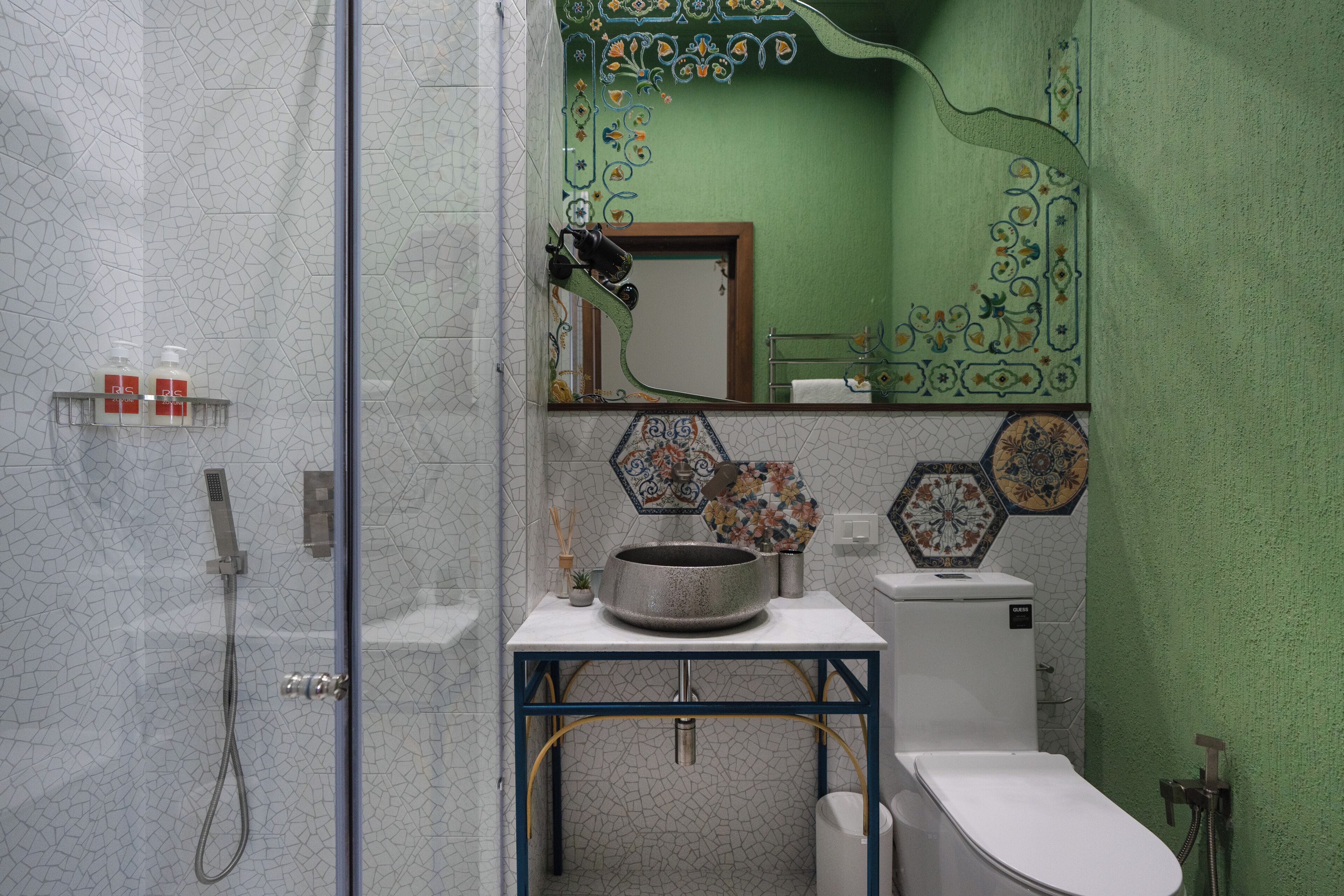 A bathroom with a shower, sink, toilet, and decorative tiles.