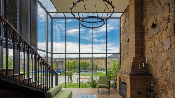 A spacious living area with a large glass wall, a fireplace, and a green sofa.