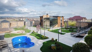 A modern building with a glass facade, a swimming pool, and a landscaped courtyard.