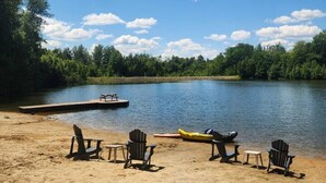A lakeside beach with a dock, chairs, and a canoe. - Mont Blanc Classic Chalet • Ski-in/Ski-out (Mont Blanc)