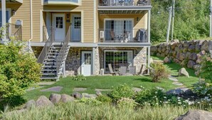 A two-story building with a stone facade, a stone retaining wall, and a well-maintained garden with rocks and grass. - Mont Blanc Classic Chalet • Ski-in/Ski-out (Mont Blanc)
