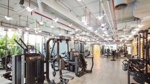 A gym with various exercise machines, a large mirror, and a spacious layout.