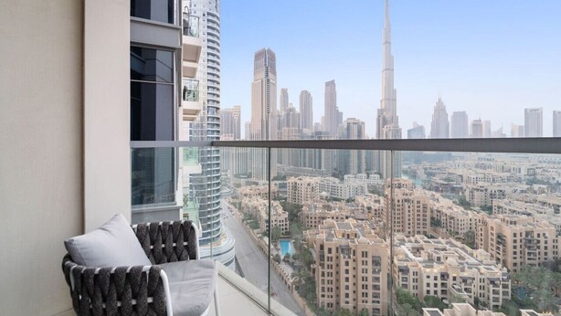 A balcony with a view of a cityscape, including a prominent skyscraper.