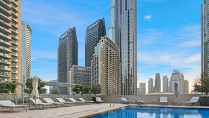 Una piscina en la azotea con sillones de descanso, rodeada de edificios altos con señalización 'EMAR'.