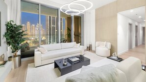Una sala moderna con un sofá blanco, una mesa de centro y vistas de un paisaje urbano a través de amplios ventanales.
