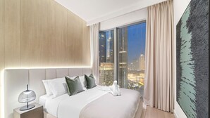 Habitación de hotel moderna con una cama grande, una mesita de noche, vistas a la ciudad y un cuadro abstracto de gran tamaño.