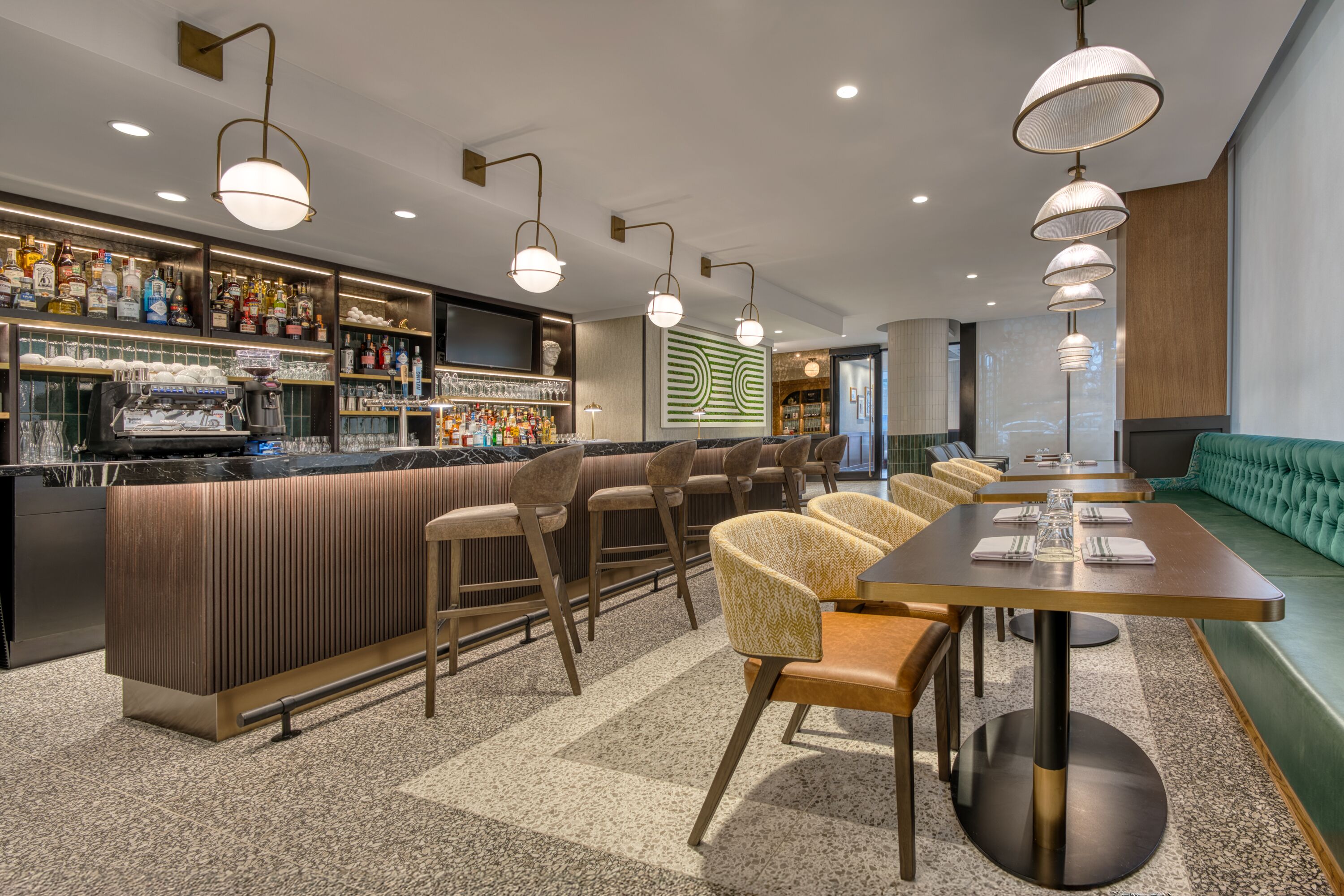 A bar area with stools, a counter with bottles, and a projection screen.