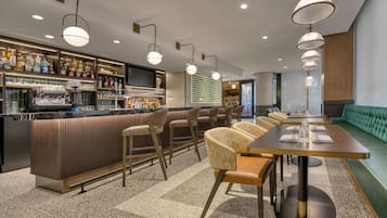 A bar area with stools, a counter with bottles, and a projection screen.