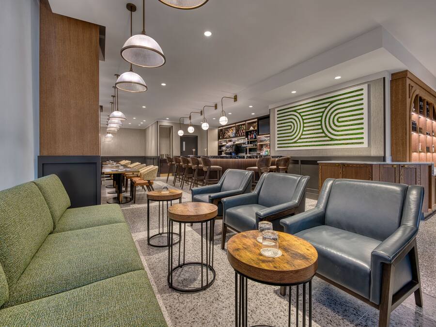 A modern lounge area with leather seating, round tables, and pendant lighting.