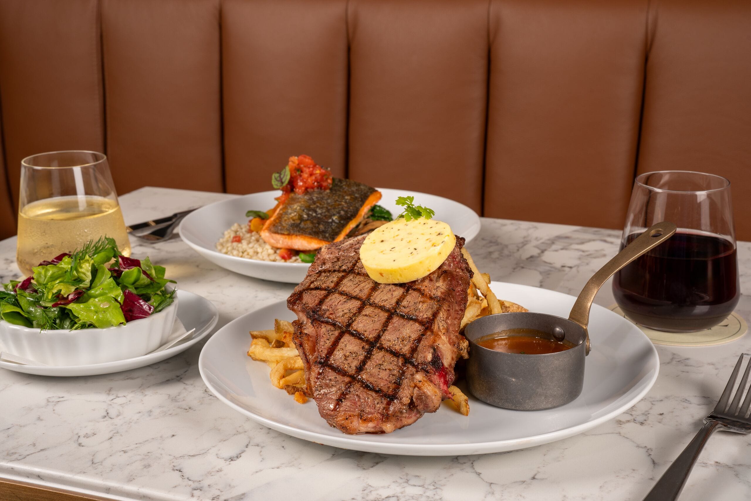 Een eettafel met een steak, friet en een salade.