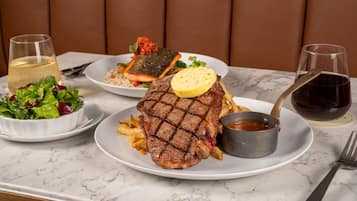 Een eettafel met een steak, friet en een salade.