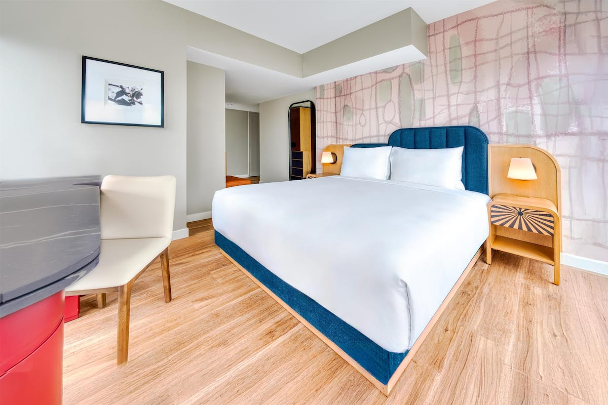 Ein modernes Hotelzimmer mit einem großen Bett, einem Schreibtisch und einem Sessel.