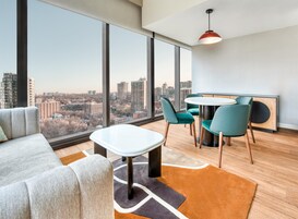 Een moderne woonkamer met uitzicht over de stad, een ronde tafel en teal stoelen.
