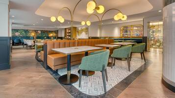 A modern restaurant interior with booths, tables, and green chairs.