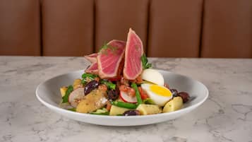 A white plate with a salad on a marble table.