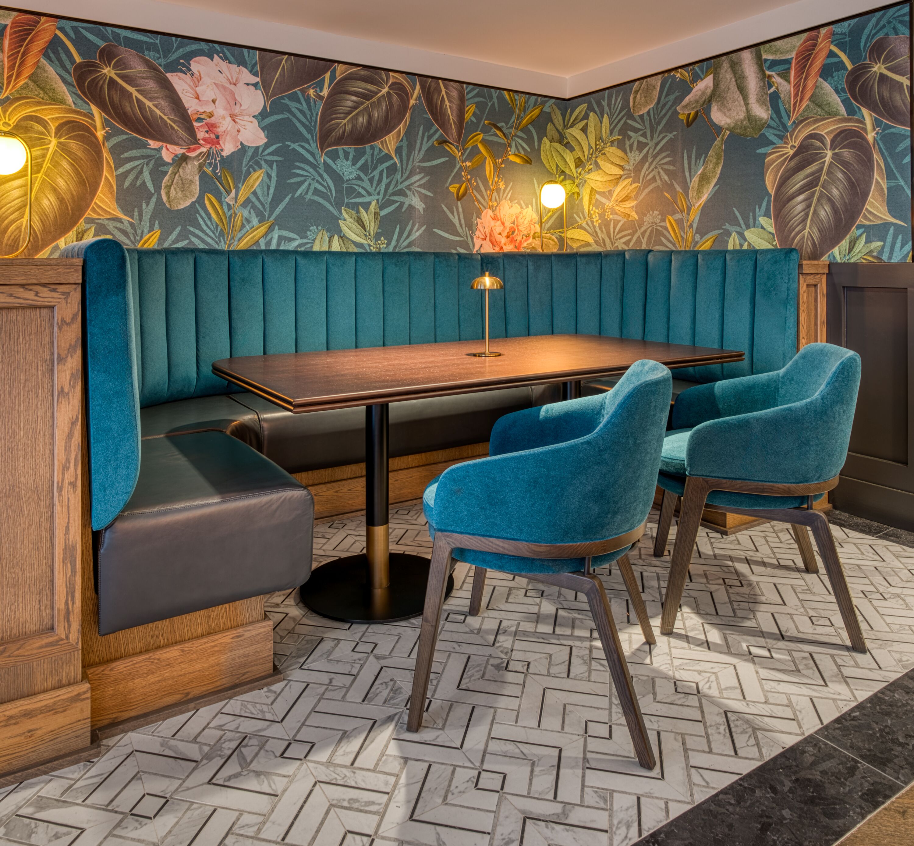 Un coin salon avec une table en bois, des chaises rembourrées en tissu bleu et un banc.