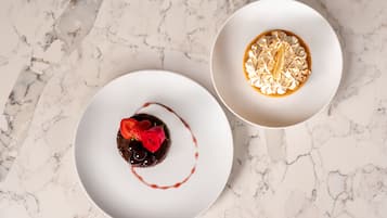 Zwei weiße Teller mit Desserts auf einer Marmorplatte.