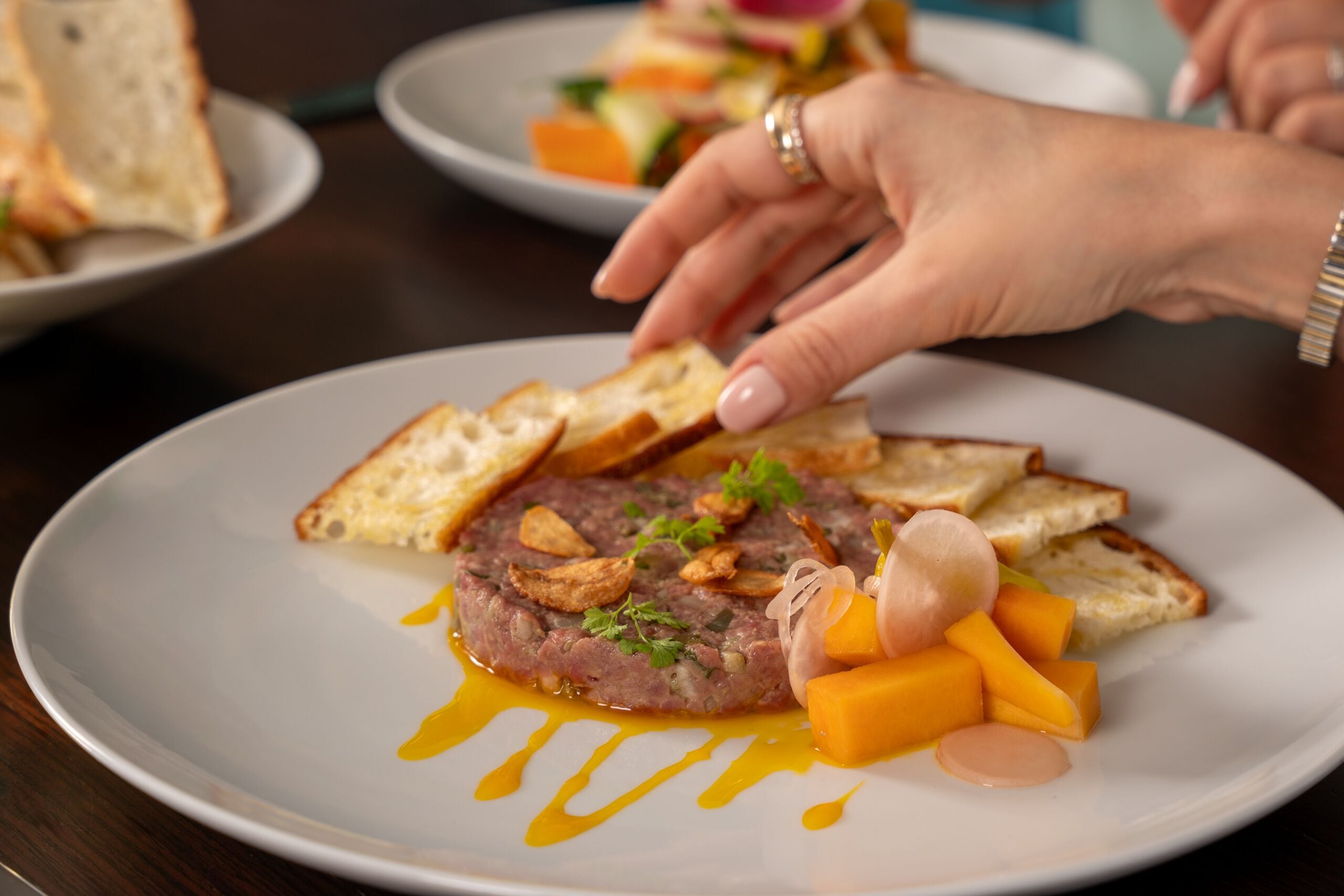 Un plato de comida con un guiso de carne, pan y verduras.