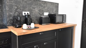 A modern kitchen with a wooden countertop, black cabinets, a coffee maker, a toaster, and a microwave. - Arum Suite with terrace (Roanne)