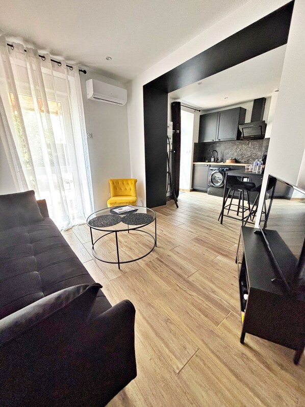 A modern living room with a sofa, a yellow armchair, a round coffee table, and a dining area with a table and chairs.