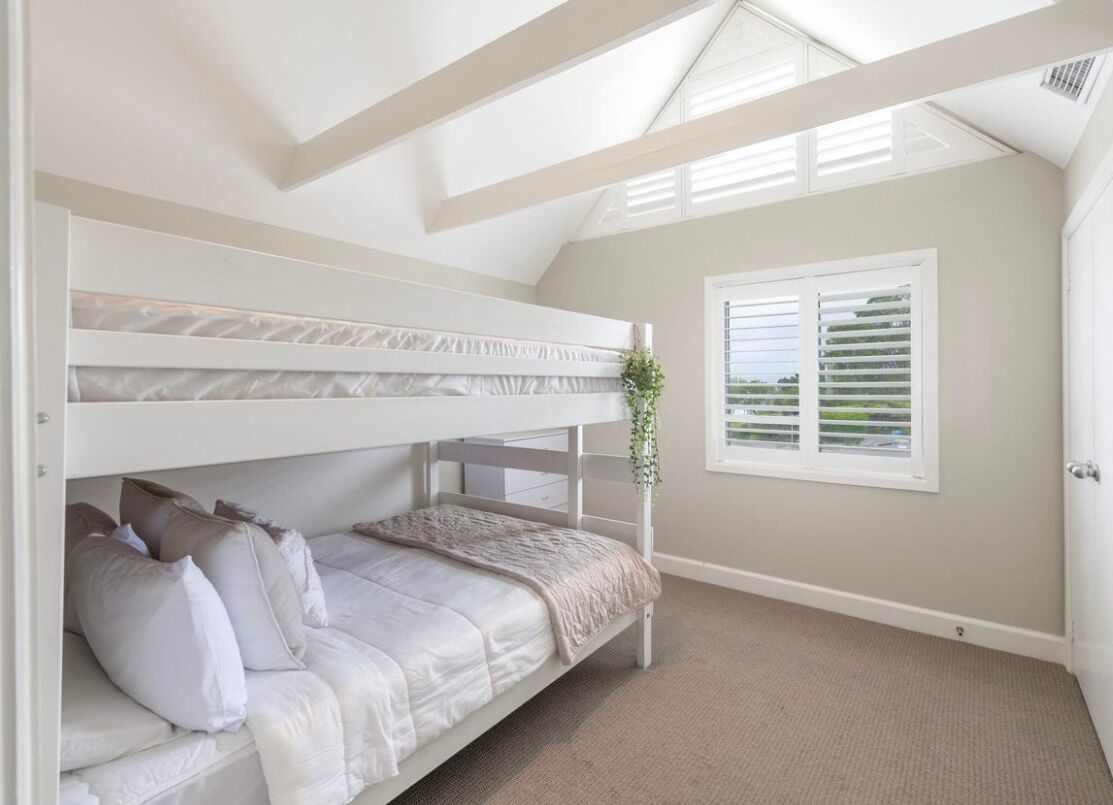 A bunk bed room with a skylight, a window with blinds, and a door.