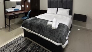 Una habitación de hotel moderna con una cama grande, un escritorio, una silla, un armario y un espejo.