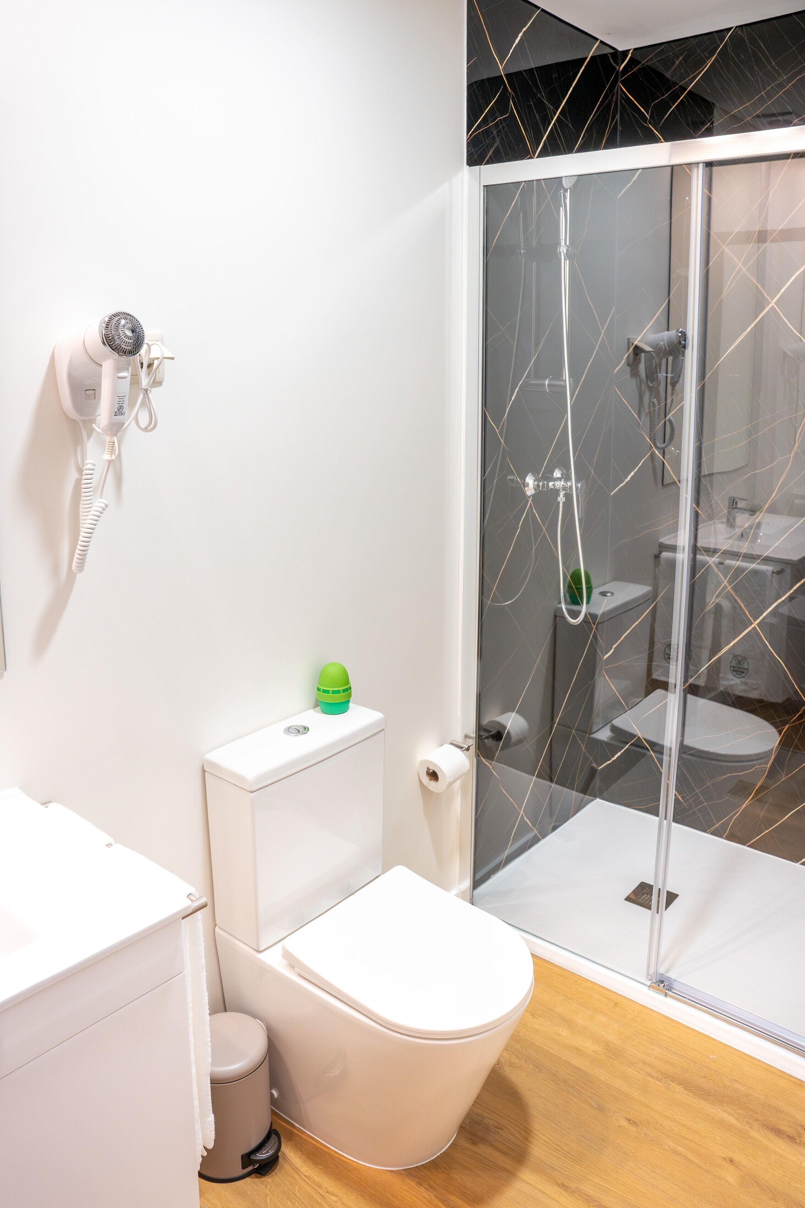 A modern bathroom with a toilet, bidet, and shower enclosure.