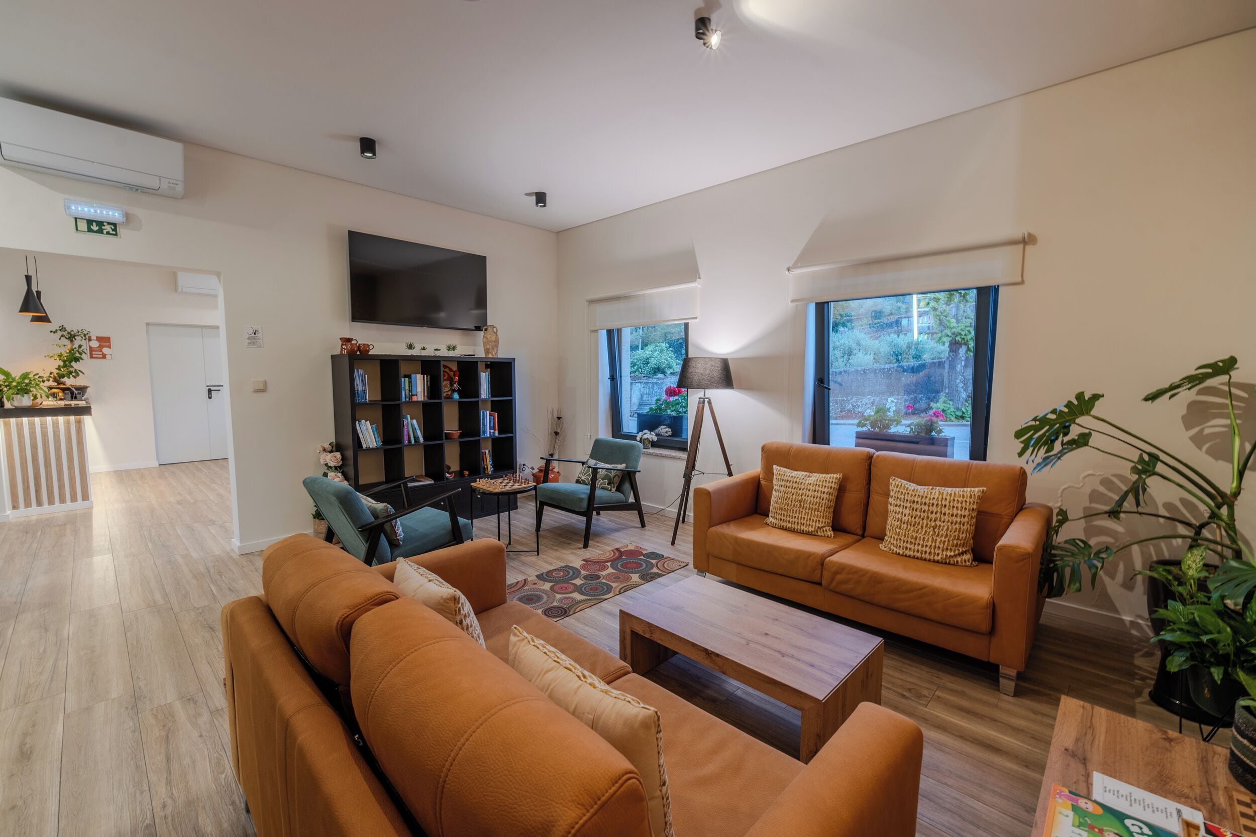 A modern living room with a sofa, armchairs, a coffee table, and a bookshelf.