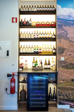 Un meuble à bouteilles contenant divers vins, un extincteur et une vitrine réfrigérée.
