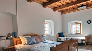 A bedroom with a wooden bed, a nightstand, a desk, and two windows with curtains. - Vineyard cottage Kovačnica (Semic)