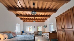 Une chambre avec deux lits, un plafond en bois, un bureau, une chaise et une armoire.