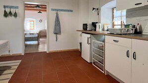 A compact kitchen with white cabinets, a small refrigerator, and a countertop with a coffee maker and microwave. - Vineyard cottage Kovačnica (Semic)