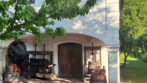 A building with a stone archway entrance, wooden barrels, and a rustic outdoor setting. - Vineyard cottage Kovačnica (Semic)