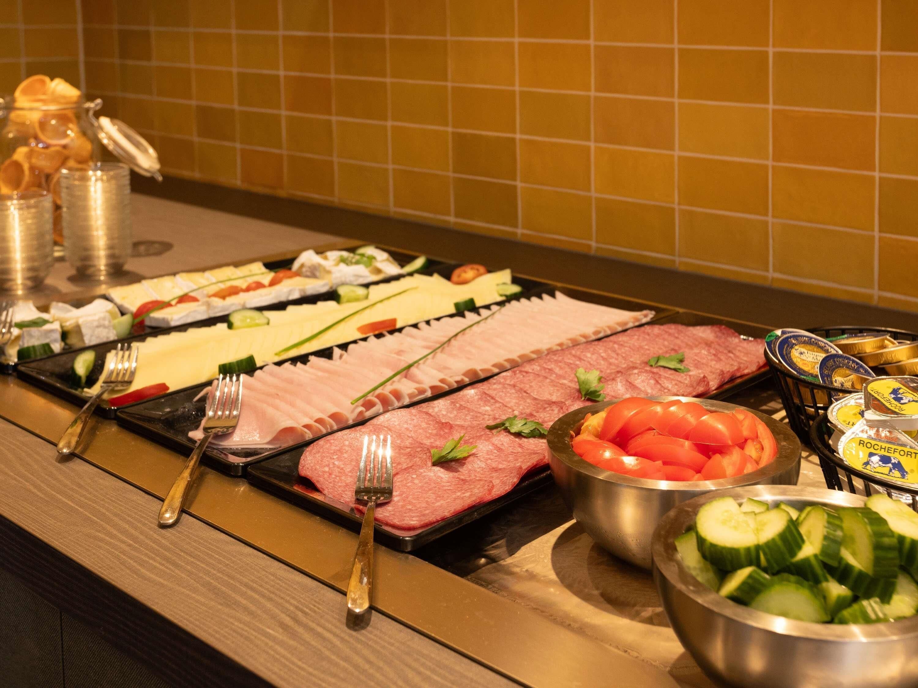 Un buffet con diverse pietanze, tra cui carni, formaggi e verdure.