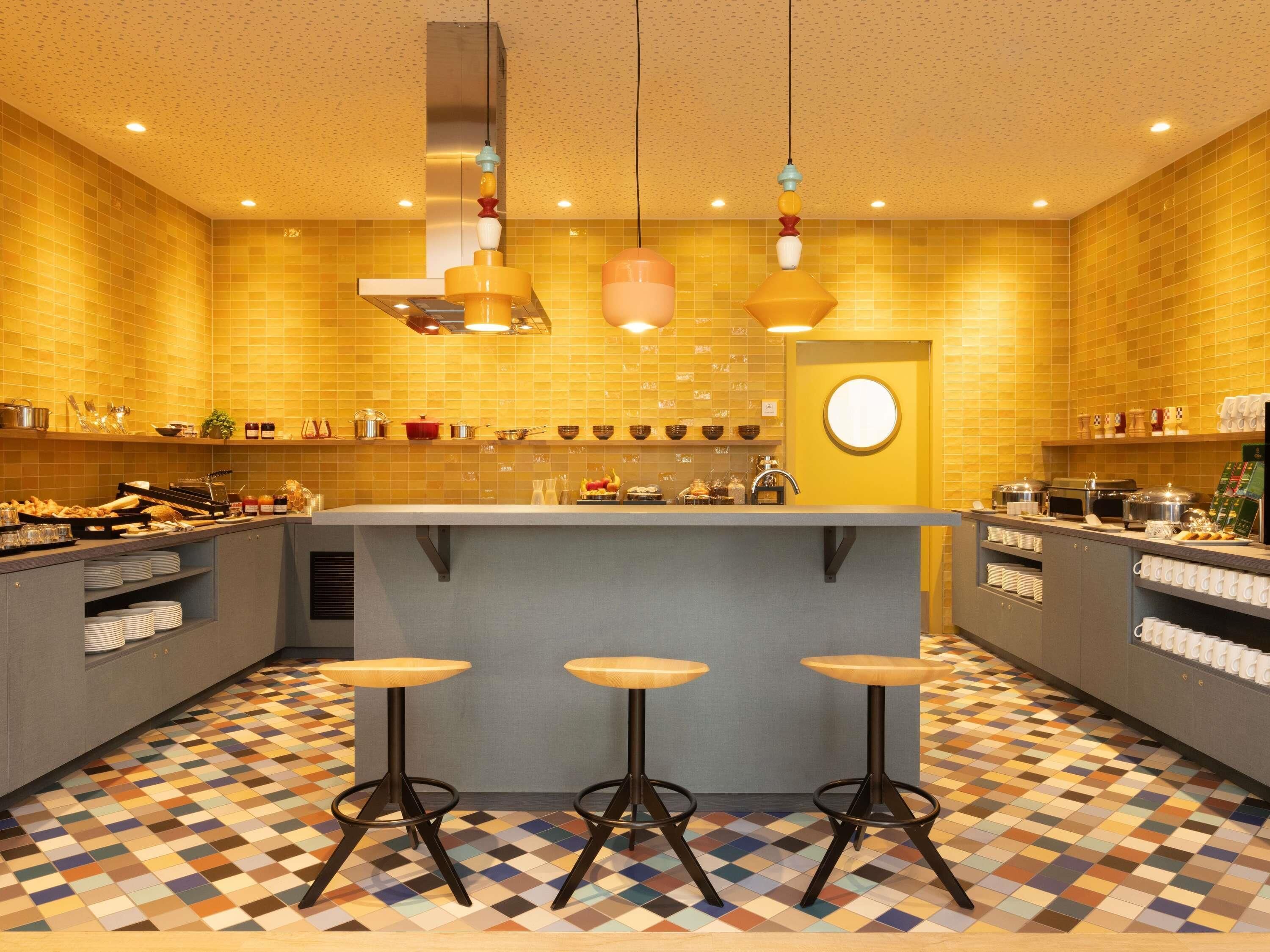 A modern kitchen with a central island, bar stools, and a patterned floor.