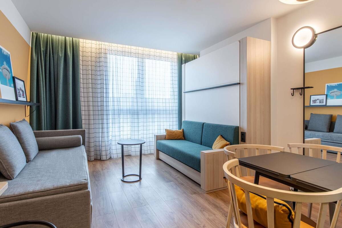 Ein modernes Wohnzimmer mit einer Couch, einem kleinen runden Tisch und einem Esstisch mit Stühlen.