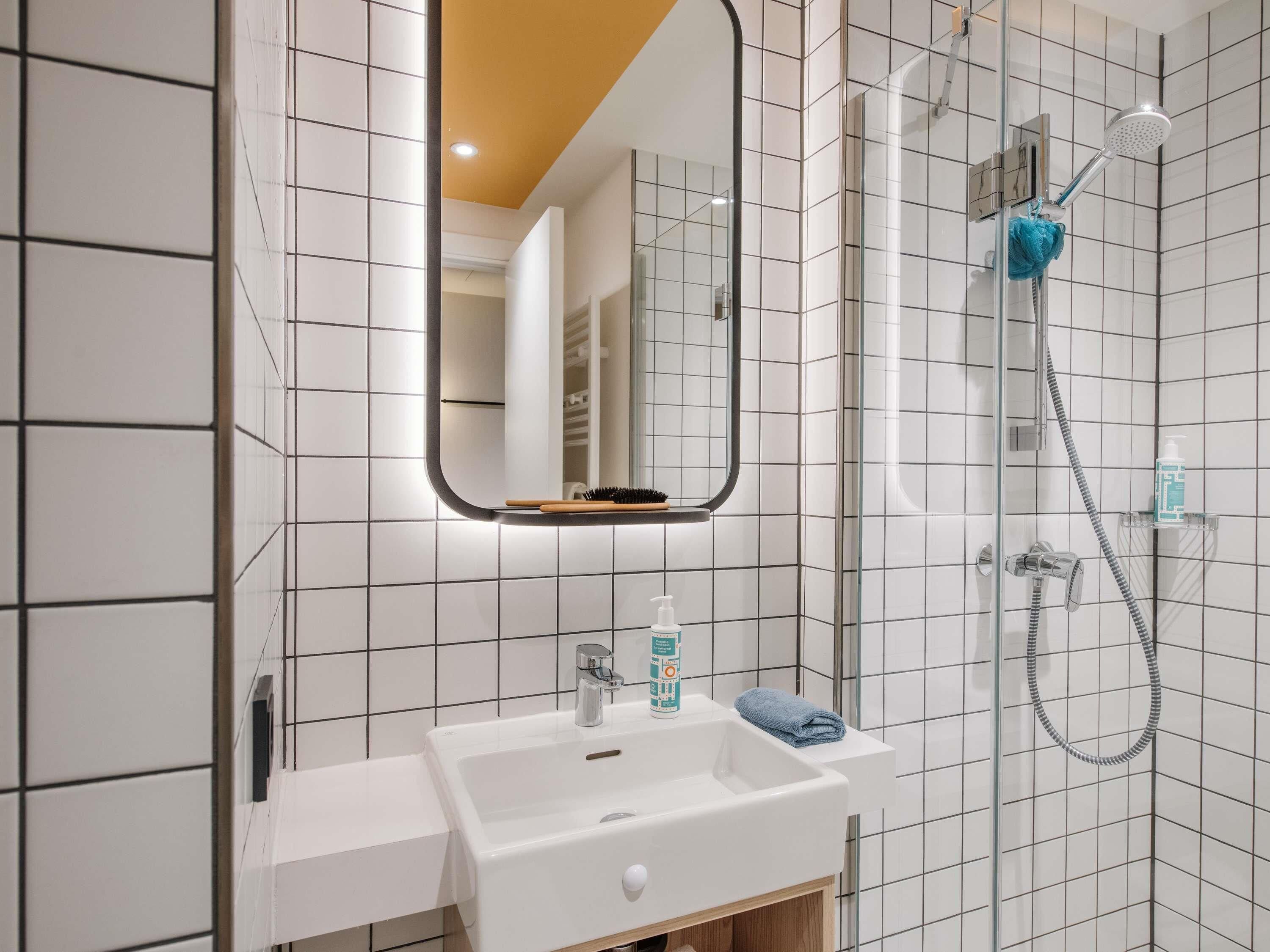 Ein modernes Badezimmer mit Waschbecken, Spiegel und Dusche.