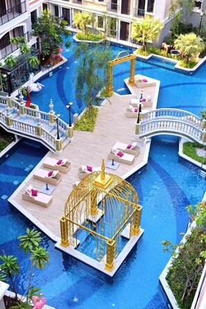 Un área de piscina interior lujosa con varios niveles, una fuente central y un pabellón dorado.